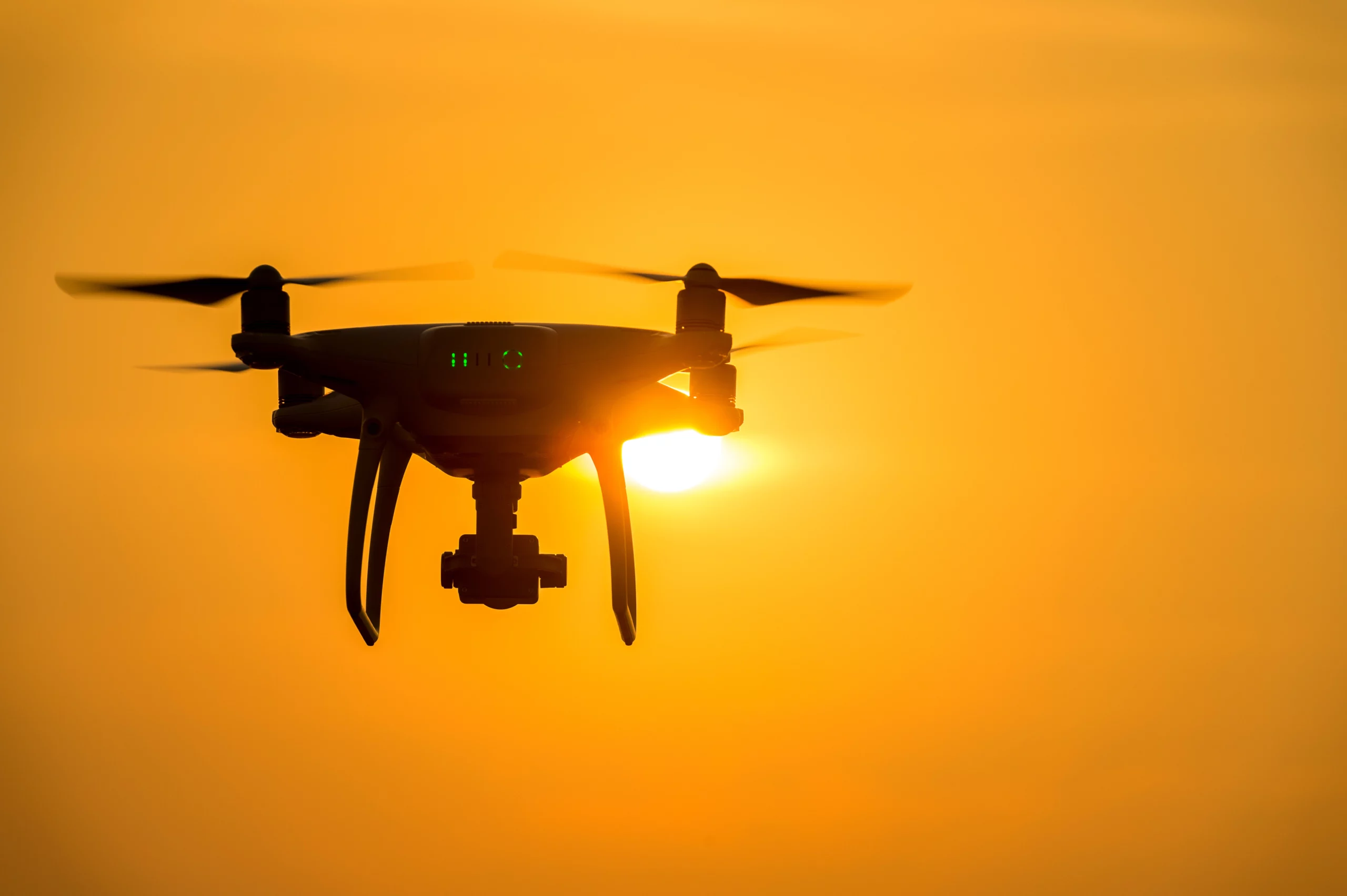 silhouette-drone-with-camera-flying-sunset